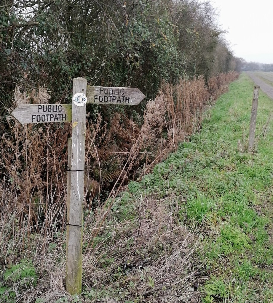 Public footpath sign on the edge of a ditch